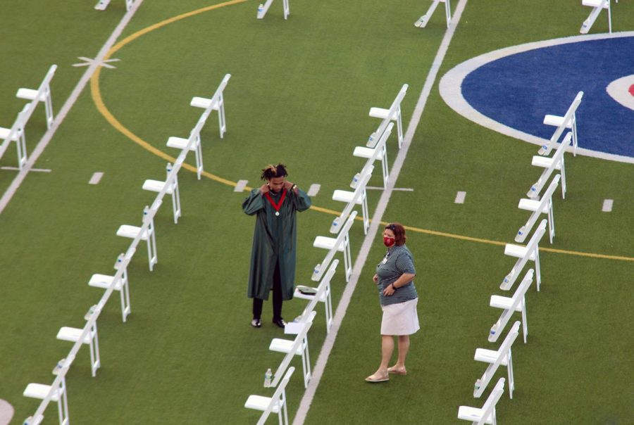 Assistant principal Debbie Shepard helps a student find his seat on the field at Woodforest during the 8 a.m. ceremony.