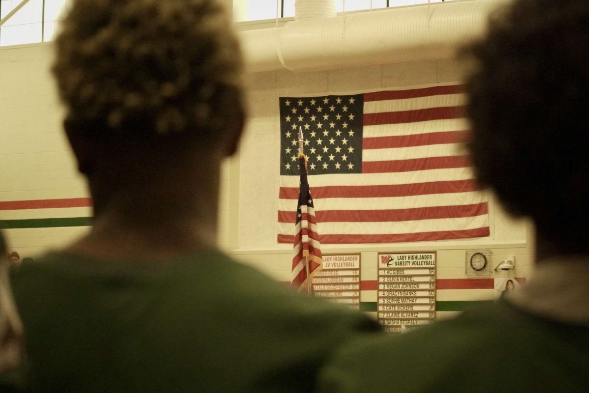 Football players at TWHS pep rally looking at the US flag.