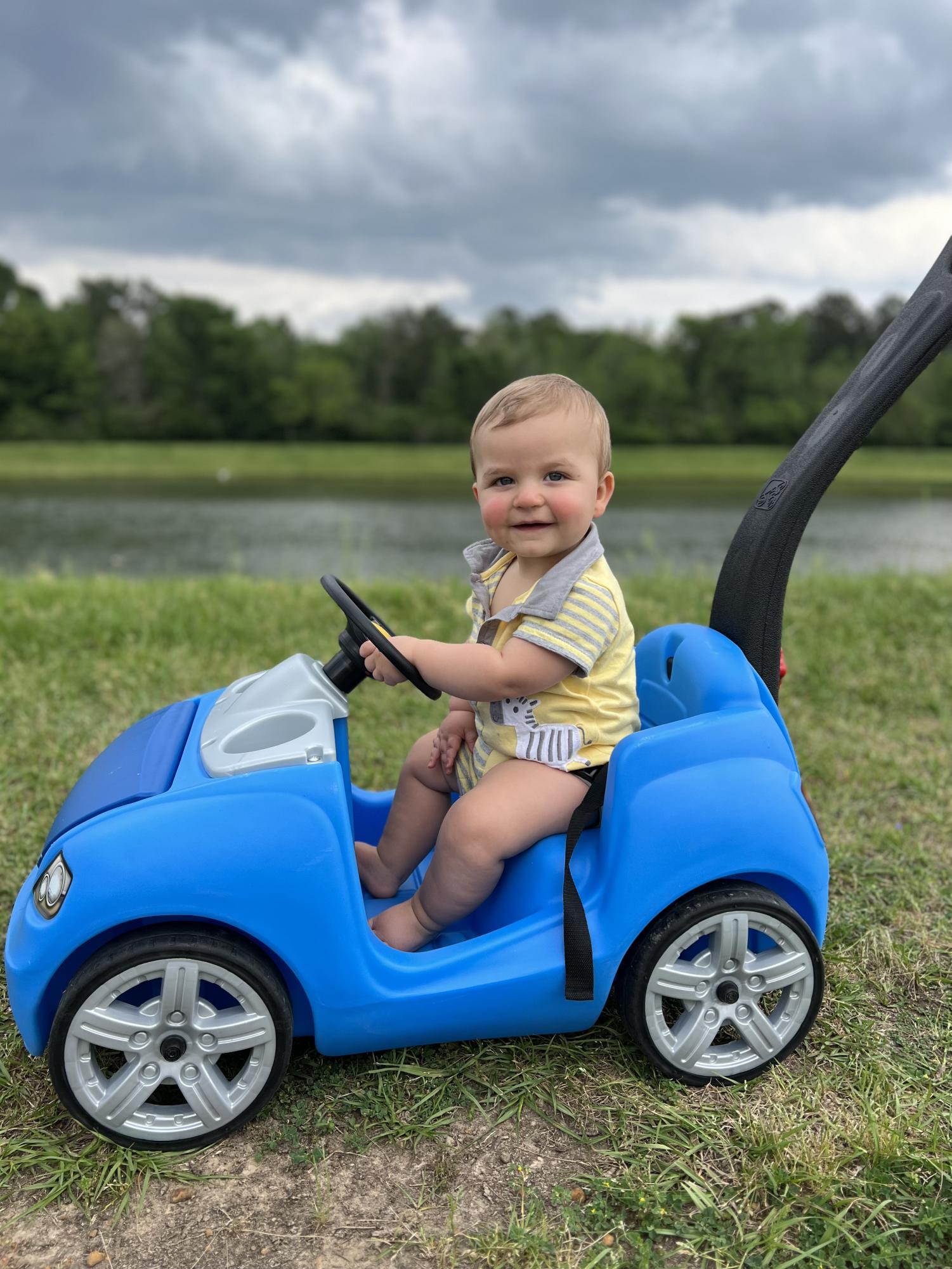 Ryder driving his toy car in front of a lake. Provided by Maggie Buckley, used with permission.