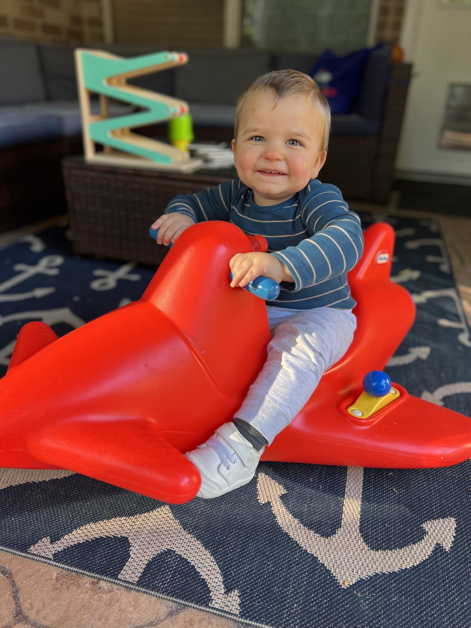 Ryder playing on a red toy airplane in his backyard. Provided by Maggie Buckley, used with permission.