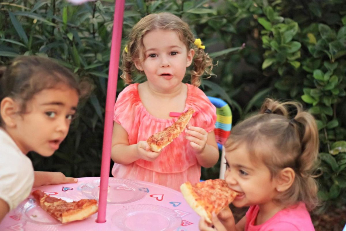 Angelina and Christina Liguori with cousin Bella Herrera as children eating pizza together at a family celebration. Photo by the Herrera Family used with permission. 